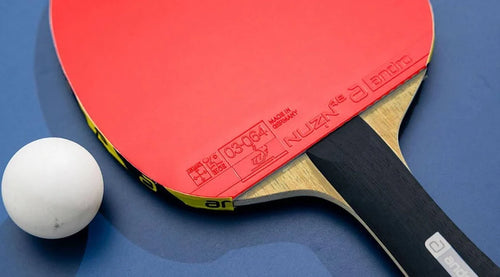 Red Andro NUZN 55 rubber fitted to a racket beside a table tennis ball